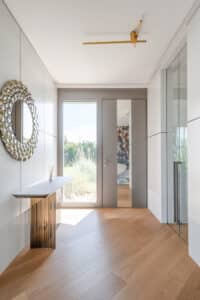Moderner Flur und Eingangsbereich mit Innenwandverkleidung und grauer Haustüre mit Spiegel und Seitenlicht von Internorm.