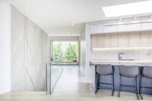 Ein moderner Flur im Obergeschoss eines Hauses mit Galerie, Treppe mit Glasgeländer, offener Wohnküche, Bar und Sitzfenster von Internorm.