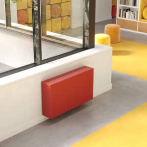 Jaga zeigt die Raumklimalösung Briza, die kühlt und heizt, in dunklem Orange als Wandmontage in einer Bücherei.