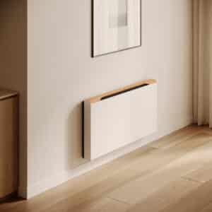 Jaga zeigt die Raumklimalösung Briza, die kühlt und heizt, in Beige als Wandmontage mit Holzabdeckung in einem Wohnraum.