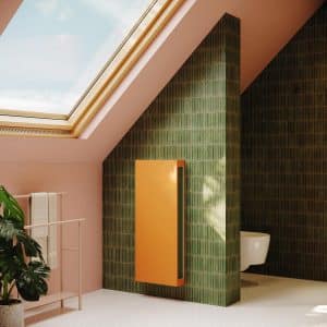 Oranger Wärmepumpen-Heizkörper VertiLina Net Zero von Jaga in einem Badezimmer.