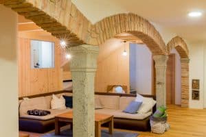 Modernes Wohnzimmer mit einer Couchlandschaft, Gewoelbebögen und Säullen von JAHN Gewölbebau.