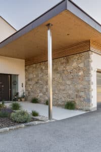 Jahn Gewölbebau zeigt eine Steinfassade im modernen Eingangsbereich eines Einfamilienhaus mit Überdachung und Metallstütze.