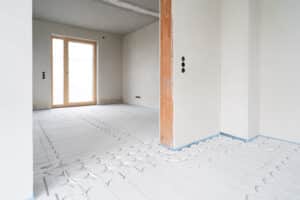 James Hardie präsentiert Trockenestrichelemente für Fußbodenheizung bei einem Übergang zwischen zwei Räumen in einem Rohbau.