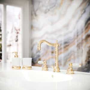 Ein Waschtisch mit 3‑Loch‑Batterie, krakelierten Porzellangriffen und Glas-Accessoires mit Armatur in edlem Messing von Jörger.