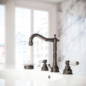 Ein Waschtisch mit 3‑Loch‑Batterie, Porzellangriffen mit Krakelierung Armatur in der Farbe Nerz von Jörger.