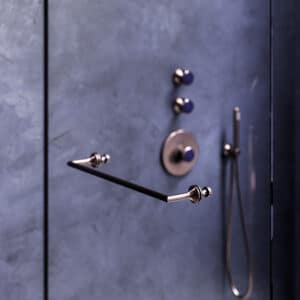 Ein Duschtürgriff mit Unterputz‑Thermostat‑Ventil‑Modul, Schlauchbrausegarnitur und blauen Aventurin‑Natursteinen im nerz-mattierten Finish von Jörger.