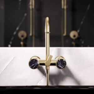 Ein Wannenfüll‑ und Brausebatterie der Serie 'Valencia' in Edelmessing-Matt, mit Aufputzmontage mit schwarzen Marmorgriffen von Jörger.