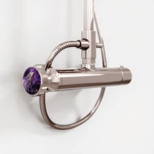 Ein Brausethermostat‑Armaturenteil aus der Serie Valencia in Platin mit violettem Amethyst‑Naturstein als Griffdetail von Jörger.