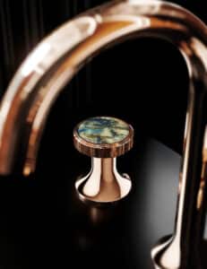 Ein Armaturelement der Serie 'Valencia' in Roségold mit Labradorit‑Naturstein‑Detail von Jörger.
