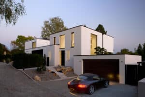 Ein modernes, verschachteltes Doppelhaus mit Flachdächern, bodentiefen Fenstern, Garagen, Balkon und Dachterrassen von Josko.