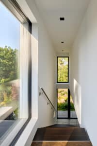 Obergeschoß eines modernen Einfamilienhauses mit schwarzgerahmter Fixverglasung, Terrassentür mit Seitenverglasung und Oberlicht von Josko.