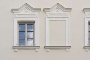 Aussenaufnahme eines Altbaus mit hellgrauen Kunststoff/Aluminium‑Sprossenfenstern und klassischem Fassadenstuck von Josko.