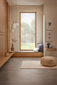 Ein kippbares Sitzfenster aus der Serie "Platin, 2. Generation" von Josko mit rahmenschlanker Holz‑Alu‑Konstruktion in Eiche in einem im Zwischen- bzw. Vorraum mit Garderobe.