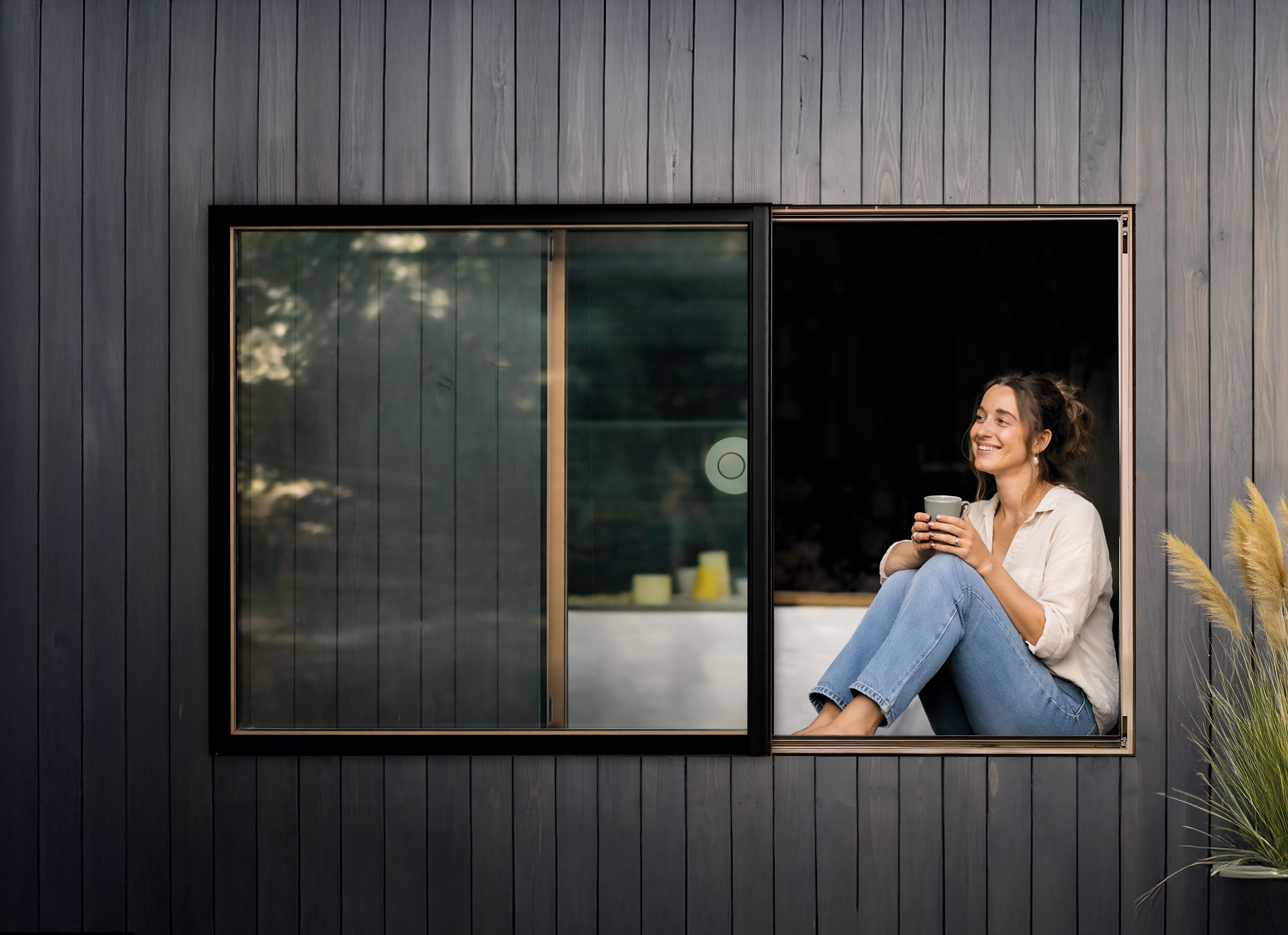KDM Innovation zeigt eine Frau auf einem Sitzfenster, das Dank Movista Fensterbeschlägen per Schieben geöffnet werden kann.