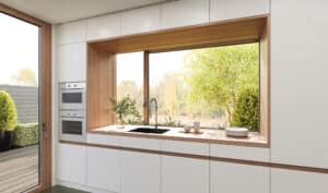 KDM Innovation zeigt eine Küche mit einem Fenster, das quer zur Arbeitsfläche verläuft und Dank Movista Fensterbeschlägen per Schieben geöffnet werden kann.
