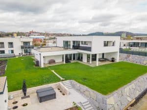 Moderne kubische Villa mit bodentiefen Glasfenstern und einem überdachten Außenbereich von B. Kern Baugesellschaft.