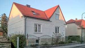 Klassisches Haus mit rotem Ziegeldach und zarter Stuckfassade in Beige von Kickinger Bau.