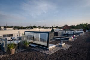 Lamilux zeigt eine Dachterrasse mit Sitzgelegenheiten, die über einen Treppenaufgang und ein großes Dachfenstern erreicht werden kann.