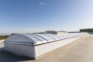 Lamilux zeigt ein langes Dachfenster mit einer Wölbung und Milchglas auf einem Flachdach.