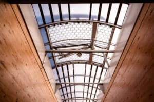 Lamilux zeigt die Innenansicht von Dachfenstern mit einer Wölbung, die sich über die ganze Breite eines Zeltdachs erstrecken.