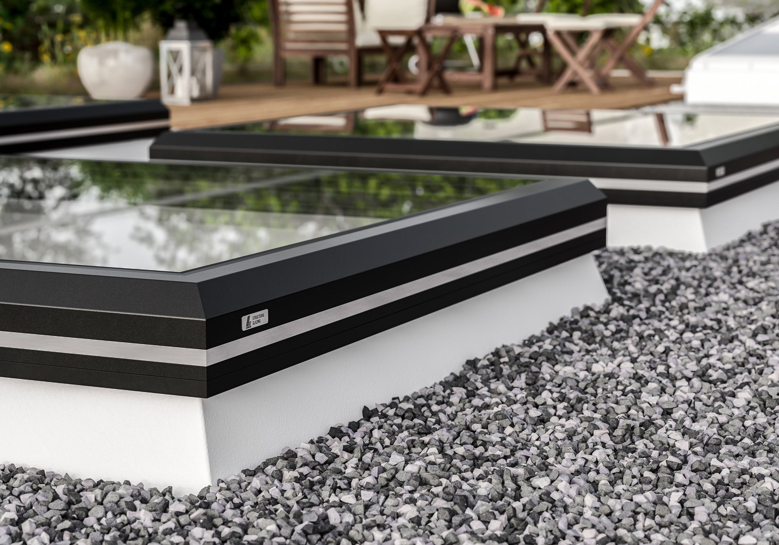 Lamilux zeigt ein Flachdach mit Kiesboden und Dachfenstern mit schwarzen Rahmen auf einer Dachterrasse.