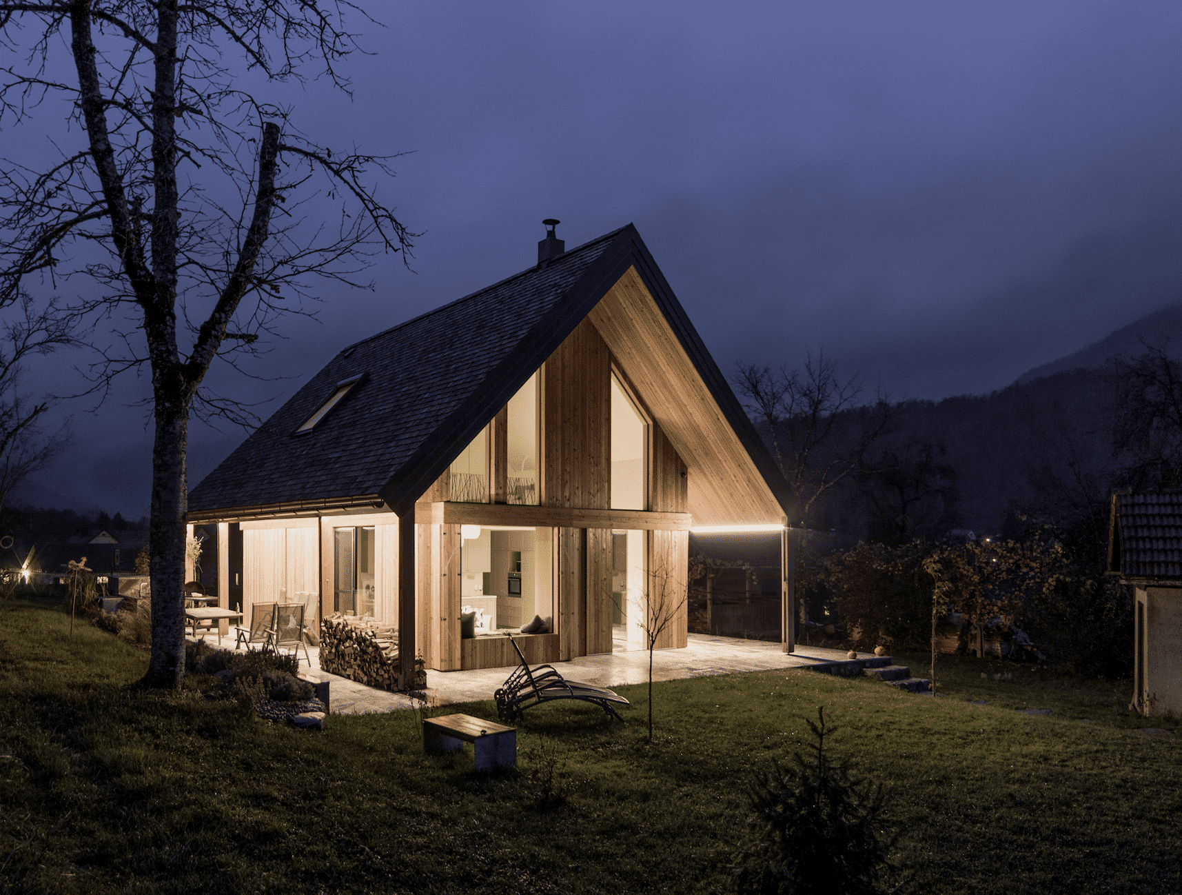 M SORA Fenster zeigt ein Wohnhaus mit toller Holzfassade und stimmungsvoller Beleuchtung.