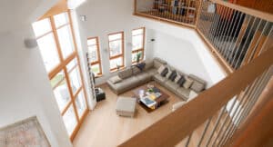 Großflächige, bodentiefe Kombination aus Holzfenster und Terrassentür mit Sprossen aus warm getöntem Holz, vermutlich Buche, dazu drei passende Fenster im Couchbereich von Maderböck lassen viel natürliches Licht in den Wohnraum des Hauses.