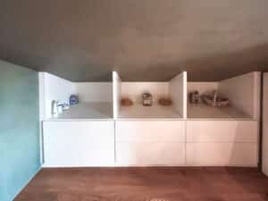 MANO Bad zeigt ein Badezimmer mit einem deckenhohen, gemauerten weissen Regal, viel Stauraum und geschickt genutzter Dachschräge.