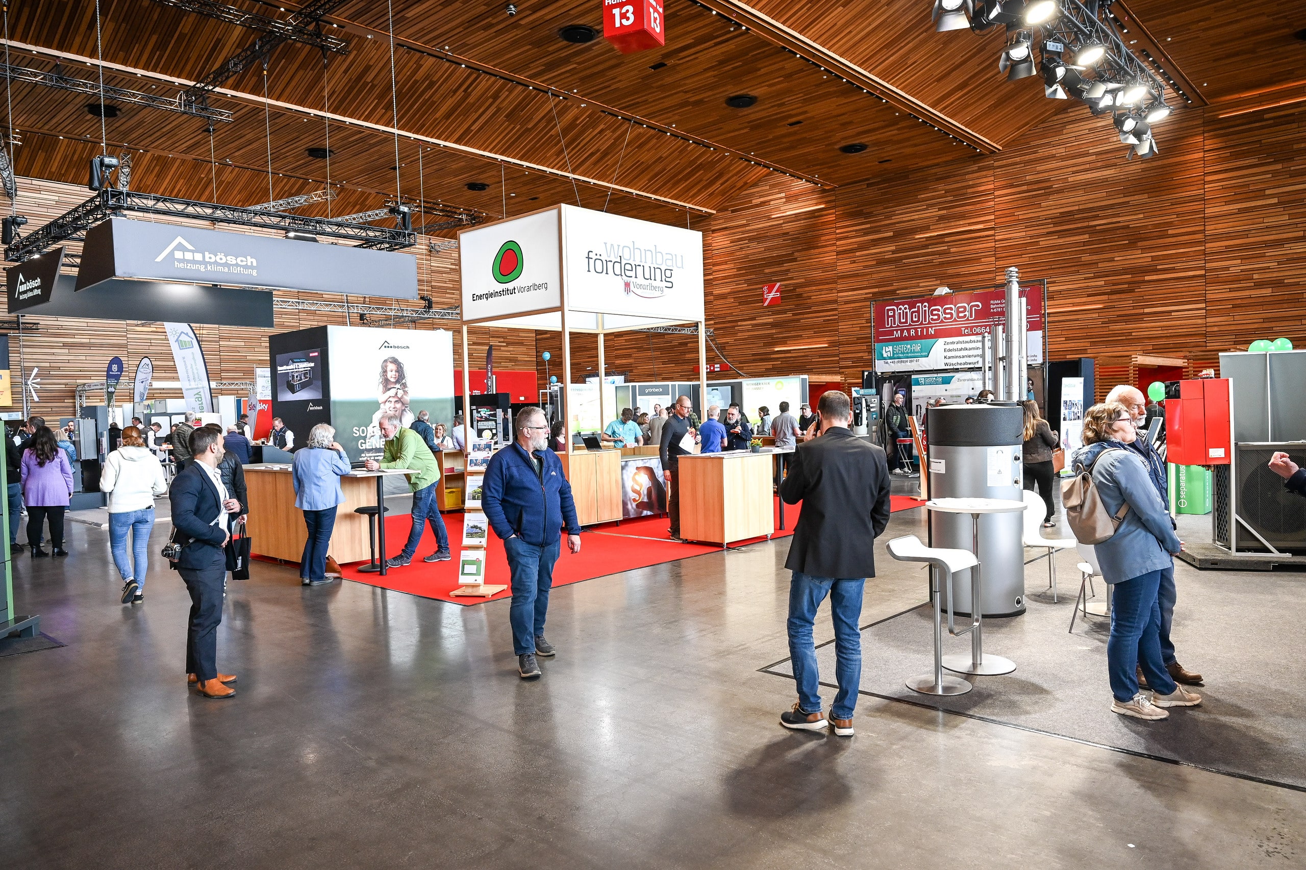 Besucher der Baumesse com:bau im Messequartier Dornbirn informieren sich an Ständen über energieeffizientes Bauen, Förderprogramme und nachhaltige Wohnbauoptionen - hier gesehen in Halle 13 bei dem auch das Energieinstitut Vorarlberg Beratungsangebote zur Wohnbauförderung vorstellt.