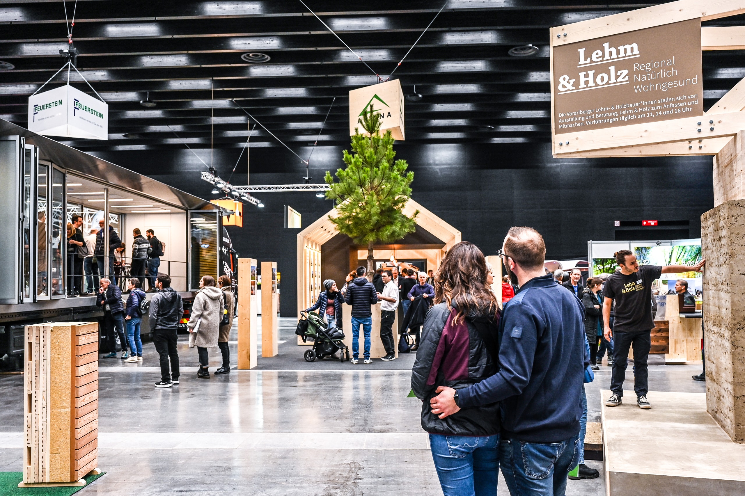 Ein Paar beim Rundgang durch eine Ausstellungshalle der Baumesse com:bau zwischen Informationsständen und Ausstellern zu Bau-, Wohn- und Einrichtungsthemen im Messequartier Dornbirn. Die com:bau bündelt Bauwirtschaft, Fachleute und Interessierte an einem Ort und bietet unabhängige Beratung zu Sanierung, Bau, Energieplanung und Finanzierung.