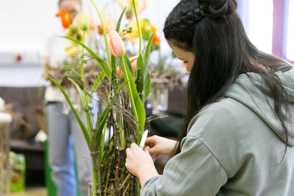 Eine Floristin bindet einen frischen Blumenstrauß und gewährt den Besuchern der Frühjahrs- und Freizeitmesse „SCHAU!“ im Messequartier Dornbirn Einblicke in Handwerk, Materialien und Gestaltung moderner Blumenkreationen bereitgestellt von der Wirtschaftskammer Vorarlberg.