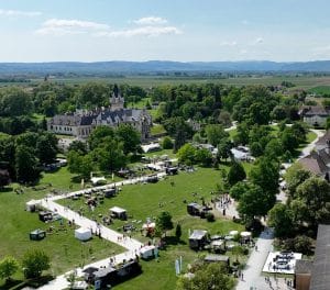 Eine Luftaufnahme der Messe Grafenegg "Design Days" zeigt einen vorbereiteten, gemusterten Weg am Schlosspark-Rasen, an dem sich die Messestände reihen und Besucher tummeln.