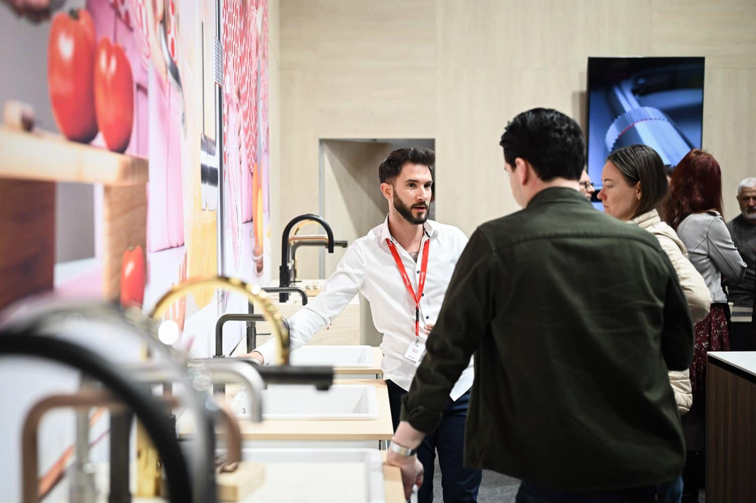 Besucher der Messe WEBUILD bei der Beratung und Produktvorführung von Küchenarmaturen.