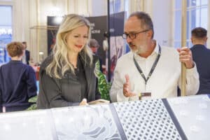 Ein Aussteller für Glas erzählt einer Besucherin über sein Produkt auf der Messe Design District 1010.