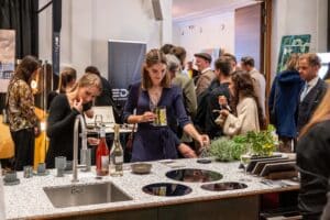Besucher der Messe Design District 1010 betrachten eine moderne Küche mit Arbeitsfläche in eleganter Terrazzo-Steinoptik.