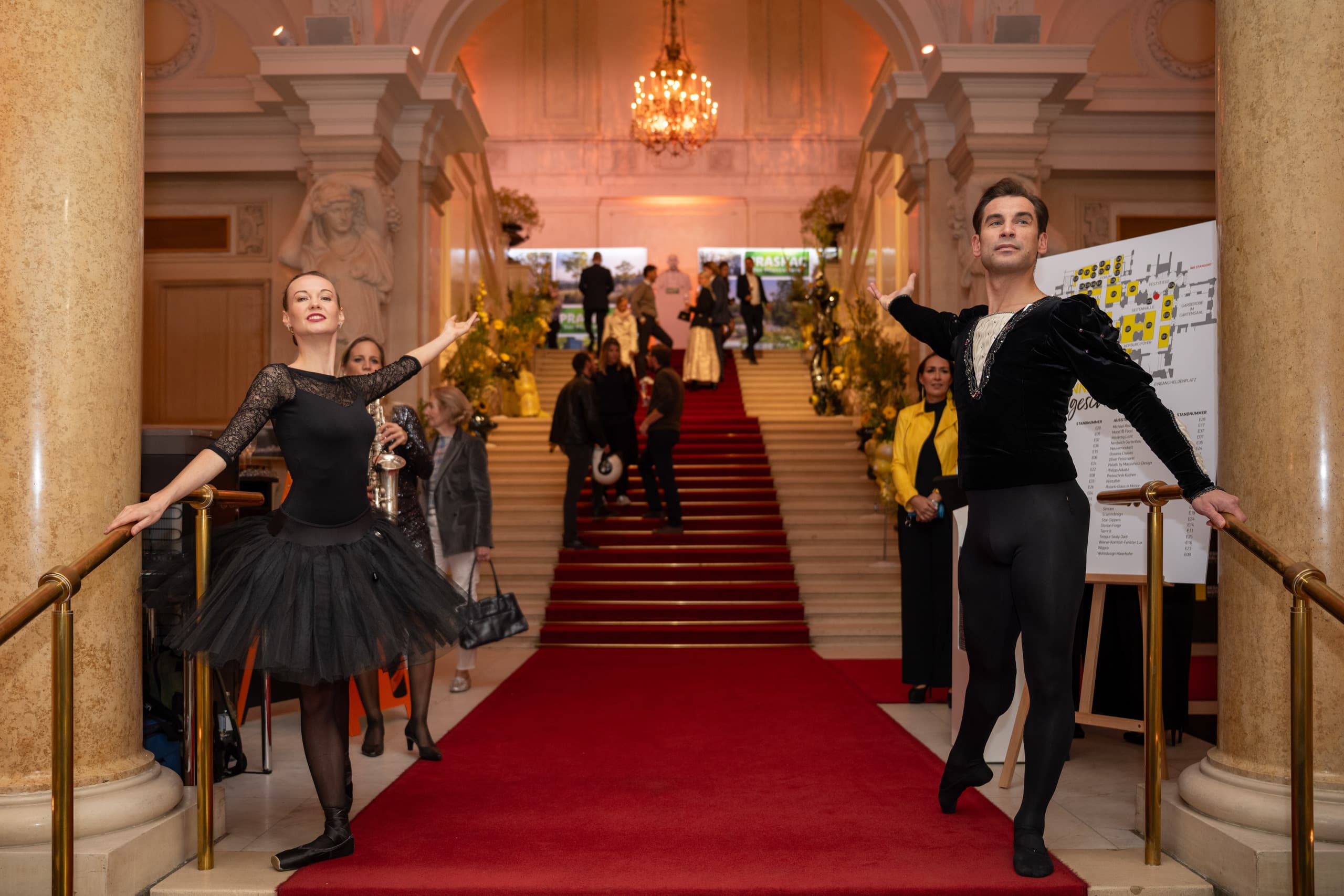 Balletttänzer und Gäste versammeln sich beim Empfang am repräsentativen Treppenaufgang der Wiener Hofburg.