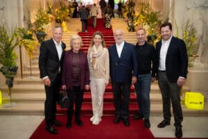 Daniel Serafin, Ingeborg Serafin und Peter Syrch posieren mit drei weiteren Personen am repräsentativen Treppenaufgang der Wiener Hofburg.