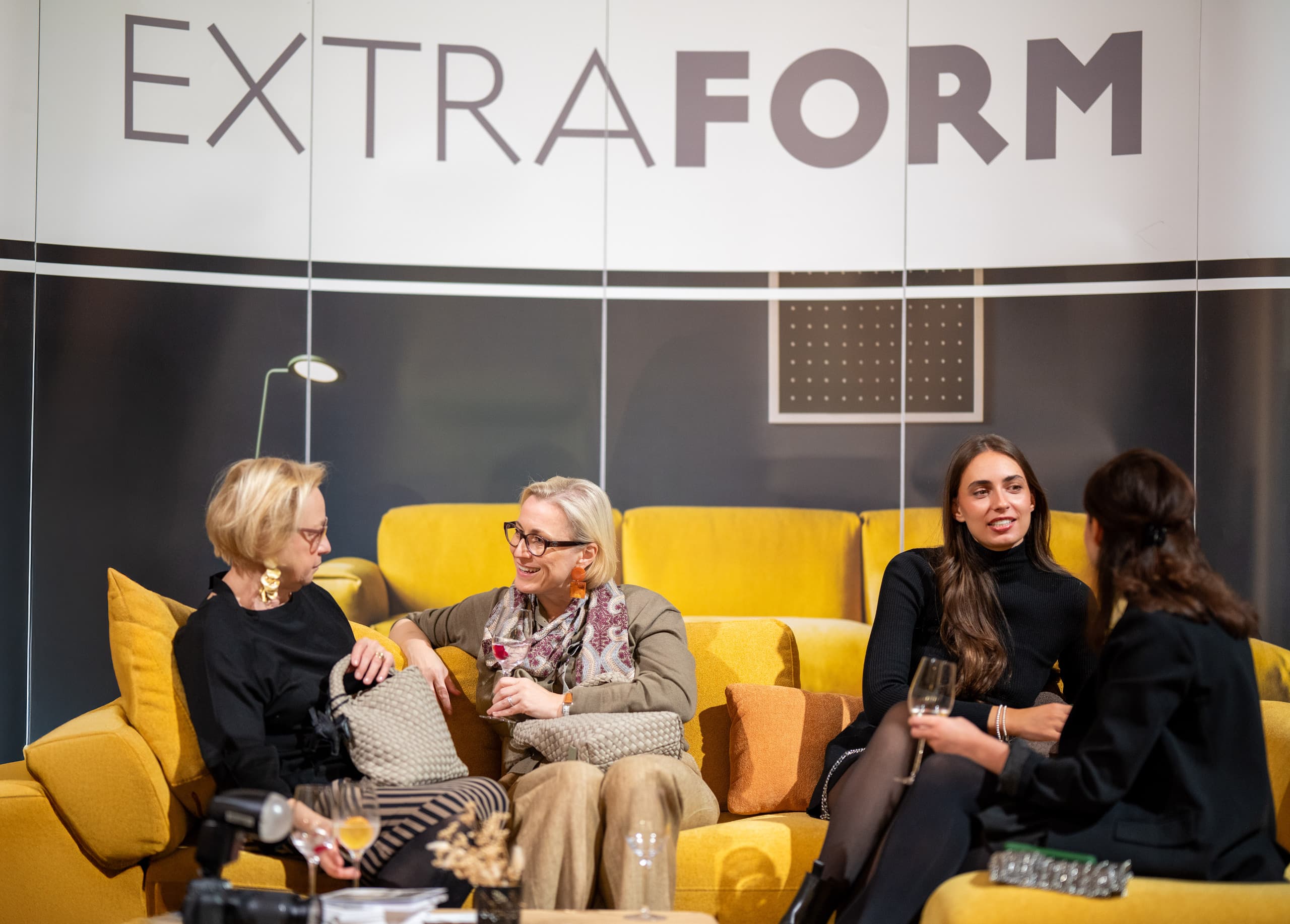 Messebesucher probieren ein hochwertiges Sofa in einer stilvollen Wohnrauminszenierung bei der Messe Design District 1010 aus.