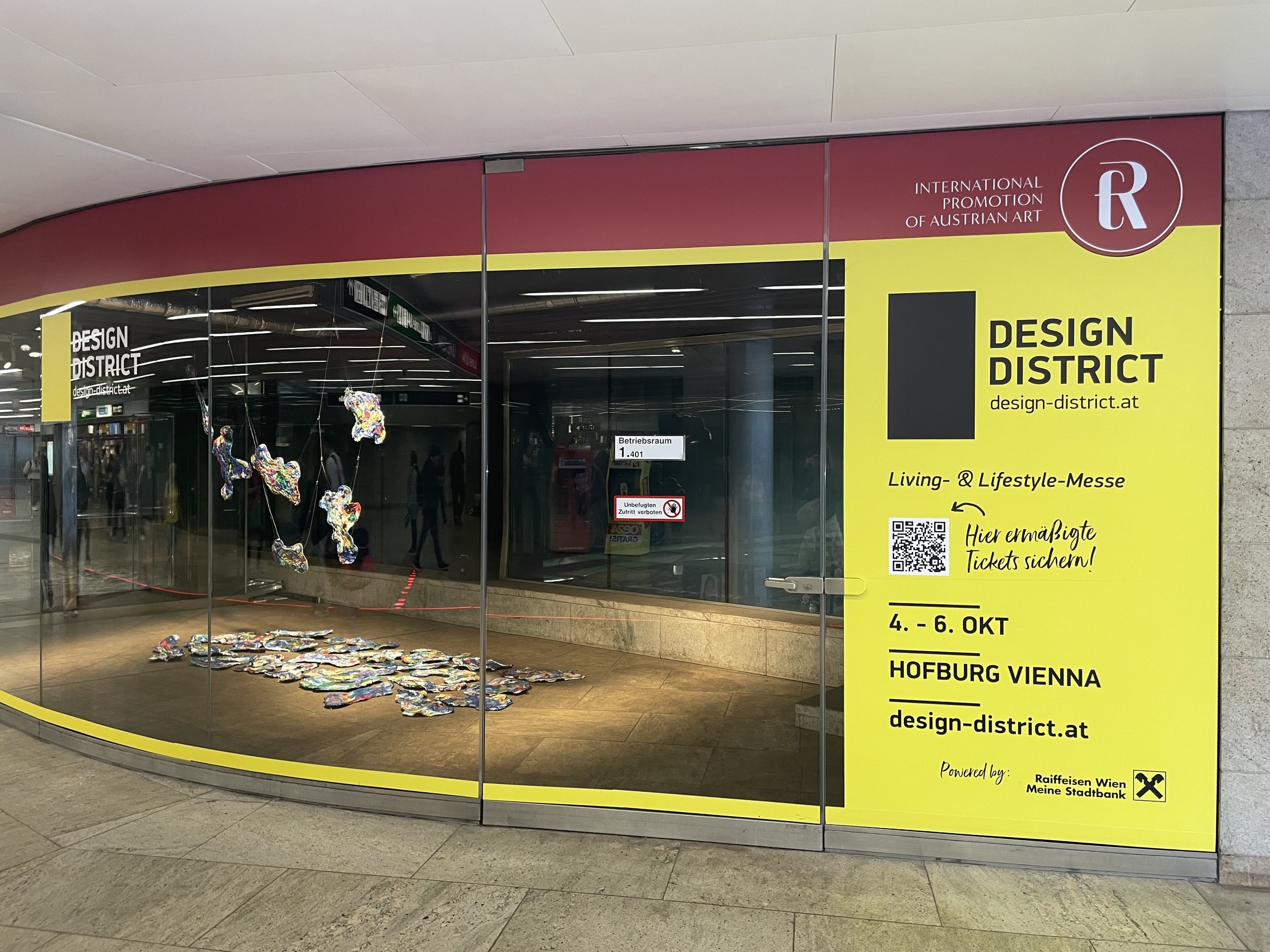 Eine kunstvolle Schaufenster-Inszenierung in der Wiener U-Bahn-Station Opernpassage lenkt volle Aufmerksamkeit auf die Design District 1010 Messe.