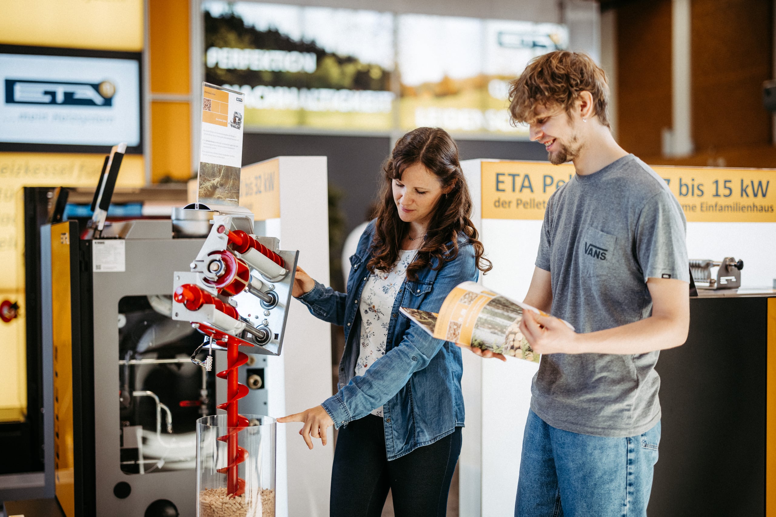 Eine Frau und ein Mann informieren sich über die Funktionsweise einer Pelletheizung und betrachten aufmerksam das technische Modell auf der Messe Wieselburg.