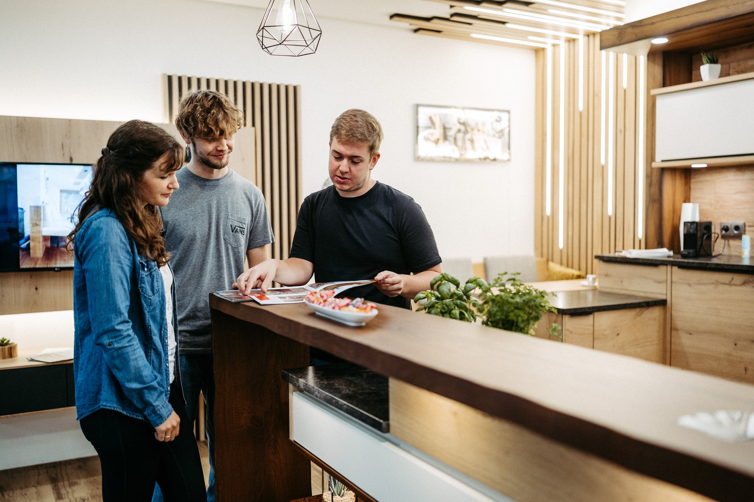 Ein Aussteller erklärt zwei Besuchern Details aus einem Produktkatalog an einer modernen Küchentheke in stilvollem Ambiente auf der Messe Wieselburg.