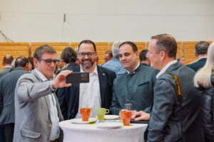 Besucherinnen und Besucher genießen die entspannte Atmosphäre beim Stehbuffet auf der Messe Bau.Energie.Wohnen in Wieselburg und halten ihre Messeerlebnisse mit einem gemeinsamen Selfie fest.