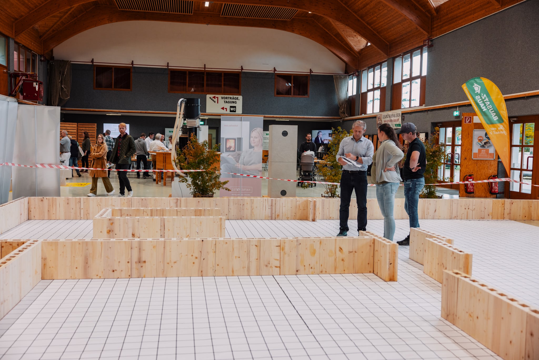 Besucherinnen und Besucher stehen im Grundriss eines begehbaren Hausplans auf der Messe Bau.Energie.Wohnen in Wieselburg.