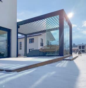 Terrasse im Winter mit Lamellenpergola mit seitlich geschlossenen Glasschiebetüren von Moltke.