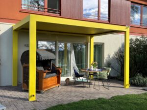 Moderne Terrasse mit Gartenbereich und knall-gelber Pergola mit Lamellendach von Moltke.