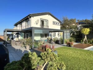 Terrasse mit Garten und moderner L-förmige Pergola in Anthrazit mit Lamellendach und Glasschiebetüren von Moltke.