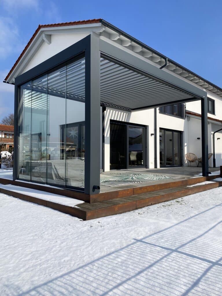 Terrasse mit erhöhtem Holzpodest, Stufen, moderner Pergola mit Lamellendach und Glasschiebetüren von Moltke.