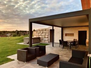 Eine moderne Pergola mit Lamellendach in Anthrazit, ausgestattet mit stilvollen Outdoor-Möbeln, die einen komfortablen und geschützten Wohnbereich im Garten schafft und zum Entspannen im Freien einlädt - von Moltke.