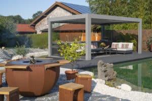 Ein moderner Garten mit Teich, Grill- und Feuerstelle und hellgrauer Pergola mit Lamellendach und offenen Glasschiebetüren von Moltke.